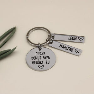 Schlüsselanhänger für den Bonus Papa aus Edelstahl mit zwei Namensanhängern für Leon und Marlene, liebevoll dekoriert.