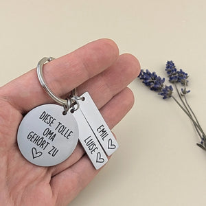 Personalisierter Tolle-Oma-Schlüsselanhänger von Gravur19 mit zwei Namen als Größenvergleich in der Hand