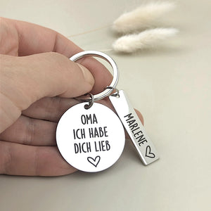 Person hält den Schlüsselanhänger „Oma, ich habe dich lieb“ mit personalisiertem Namensanhänger in der Hand.