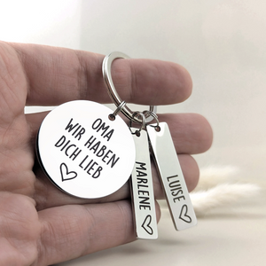 Person hält den Schlüsselanhänger „Oma, wir haben dich lieb“ mit personalisierten Namensanhängern in der Hand.