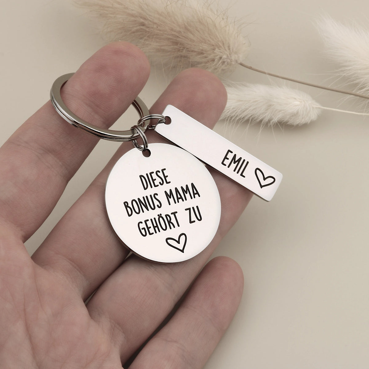 Personalisierter Bonus-Mama-Schlüsselanhänger mit Namensanhänger Emil in einer Hand.