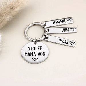 Schlüsselanhänger „Stolze Mama von“ mit Marlene, Luise und Oskar neben heller Dekoration.