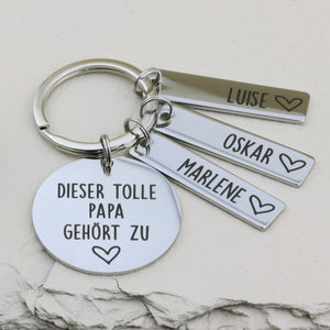 Schlüsselanhänger „Dieser tolle Papa gehört zu“ mit drei Namensanhängern Luise, Oskar und Marlene.
