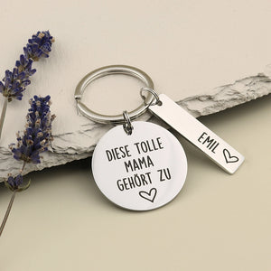 Tolle-Mama-Schlüsselanhänger „Diese tolle Mama gehört zu“ mit Namensanhänger Emil neben Lavendel