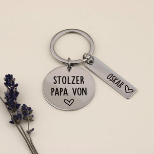 Schlüsselanhänger „Stolzer Papa von“ mit Namensanhänger Oskar und Lavendel dekoriert.