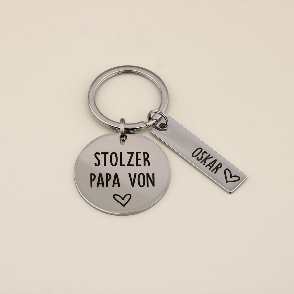 Schlüsselanhänger „Stolzer Papa von“ mit personalisiertem Namensanhänger Oskar auf hellem Hintergrund.