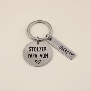 Schlüsselanhänger „Stolzer Papa von“ mit personalisiertem Namensanhänger Oskar auf hellem Hintergrund.