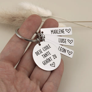 Runder Schlüsselanhänger für Tante in der Hand gehalten, silberfarbener Edelstahl mit drei personalisierten Namensanhängern: Marlene, Luise und Leon.