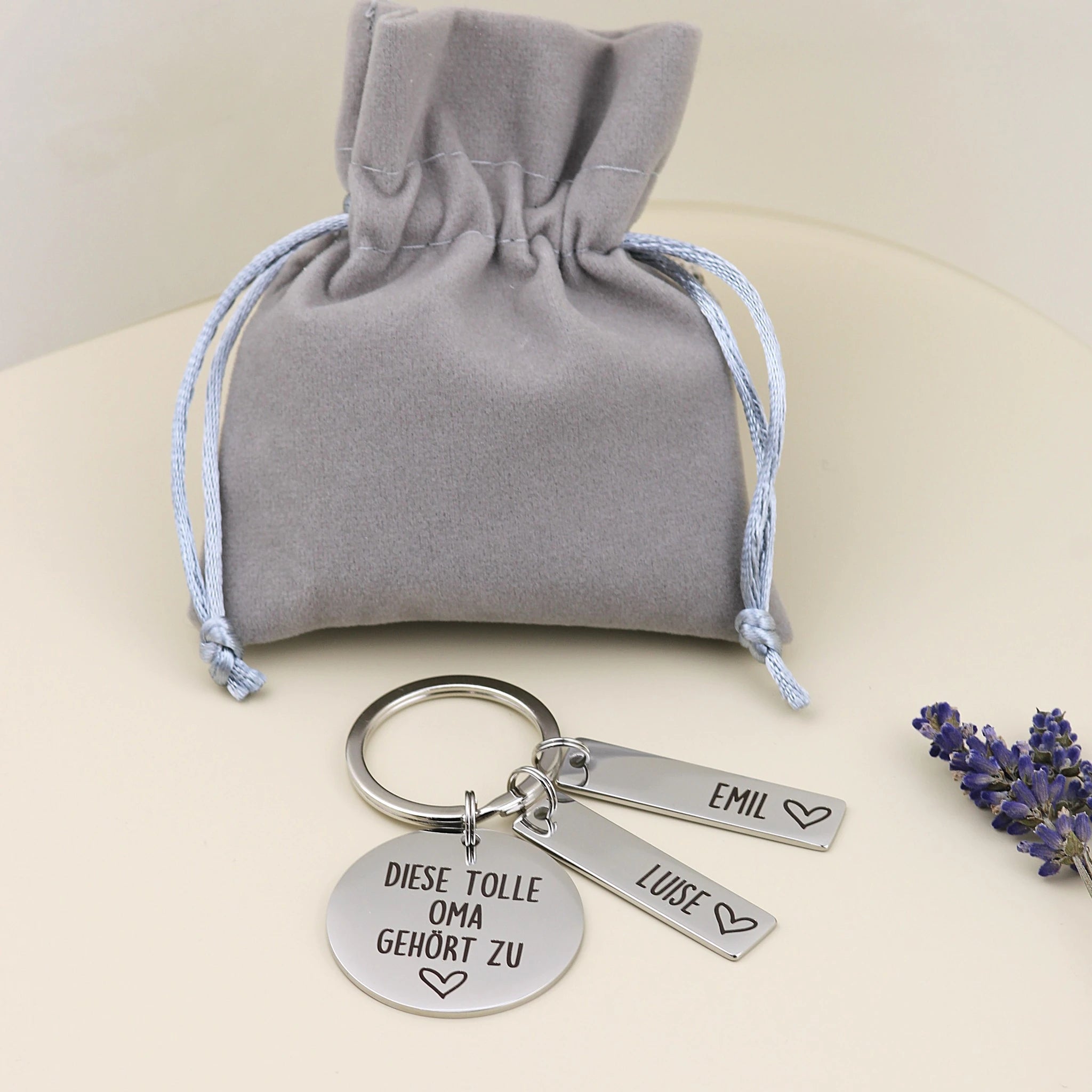 Personalisierter Tolle-Oma-Schlüsselanhänger von Gravur19 mit zwei Namensanhängern und grauem Geschenkbeutel