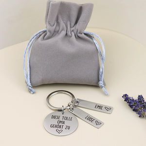 Personalisierter Tolle-Oma-Schlüsselanhänger von Gravur19 mit zwei Namensanhängern und grauem Geschenkbeutel