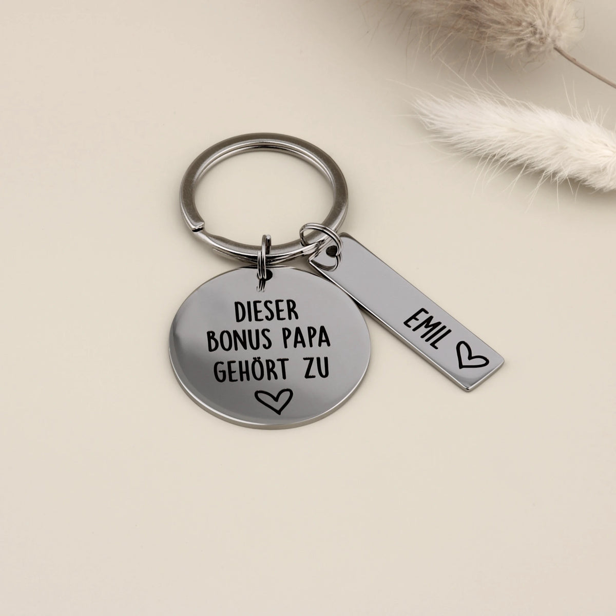 Personalisierter Schlüsselanhänger für den Bonus Papa aus hochglanzpoliertem Edelstahl mit einem Namensanhänger für Emil.
