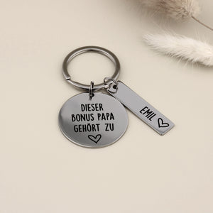 Personalisierter Schlüsselanhänger für den Bonus Papa aus hochglanzpoliertem Edelstahl mit einem Namensanhänger für Emil.
