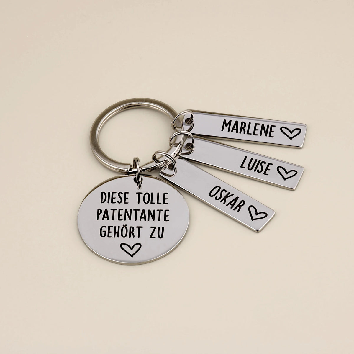 Schlüsselanhänger „Diese tolle Patentante gehört zu“ mit den Namensanhängern Marlene, Luise und Oskar.