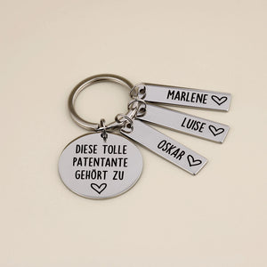 Schlüsselanhänger „Diese tolle Patentante gehört zu“ mit den Namensanhängern Marlene, Luise und Oskar.