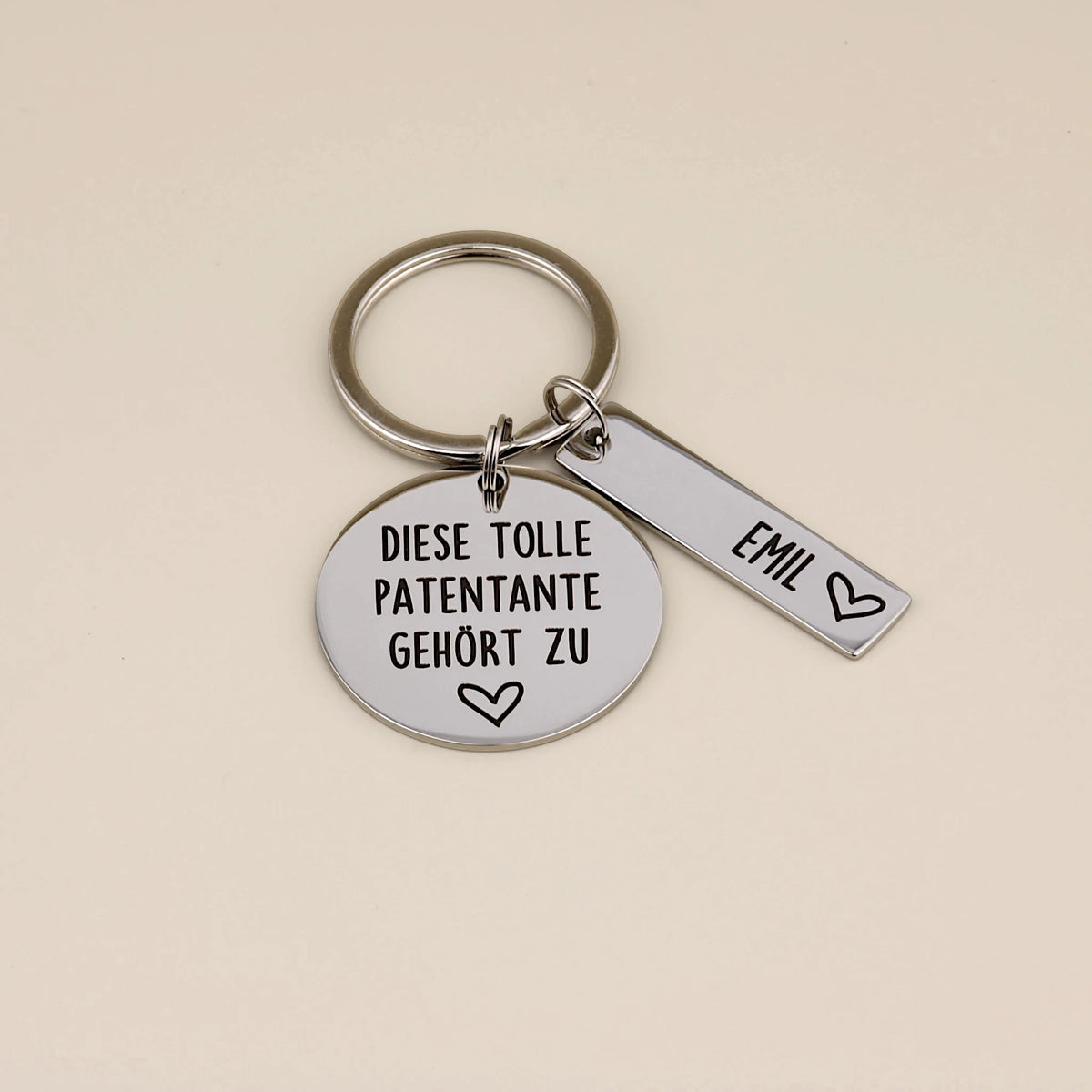 Schlüsselanhänger „Diese tolle Patentante gehört zu“ mit Namensanhänger Emil auf hellem Hintergrund.
