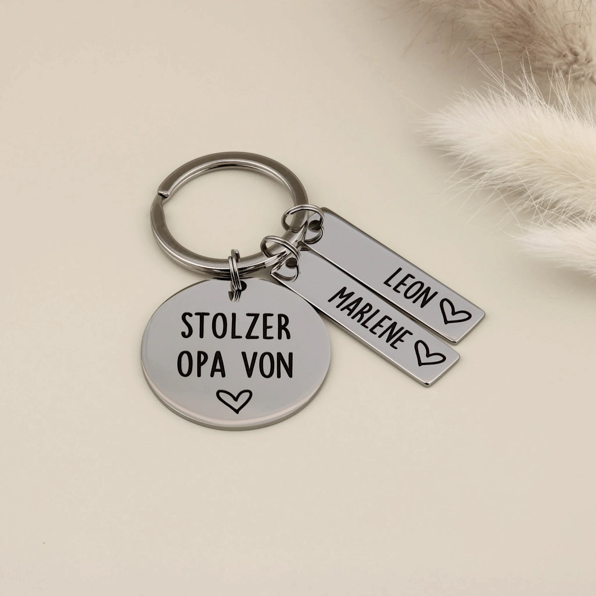 Opa-Schlüsselanhänger mit Gravur „Stolzer Opa von“ und zwei personalisierten Namensanhängern.
