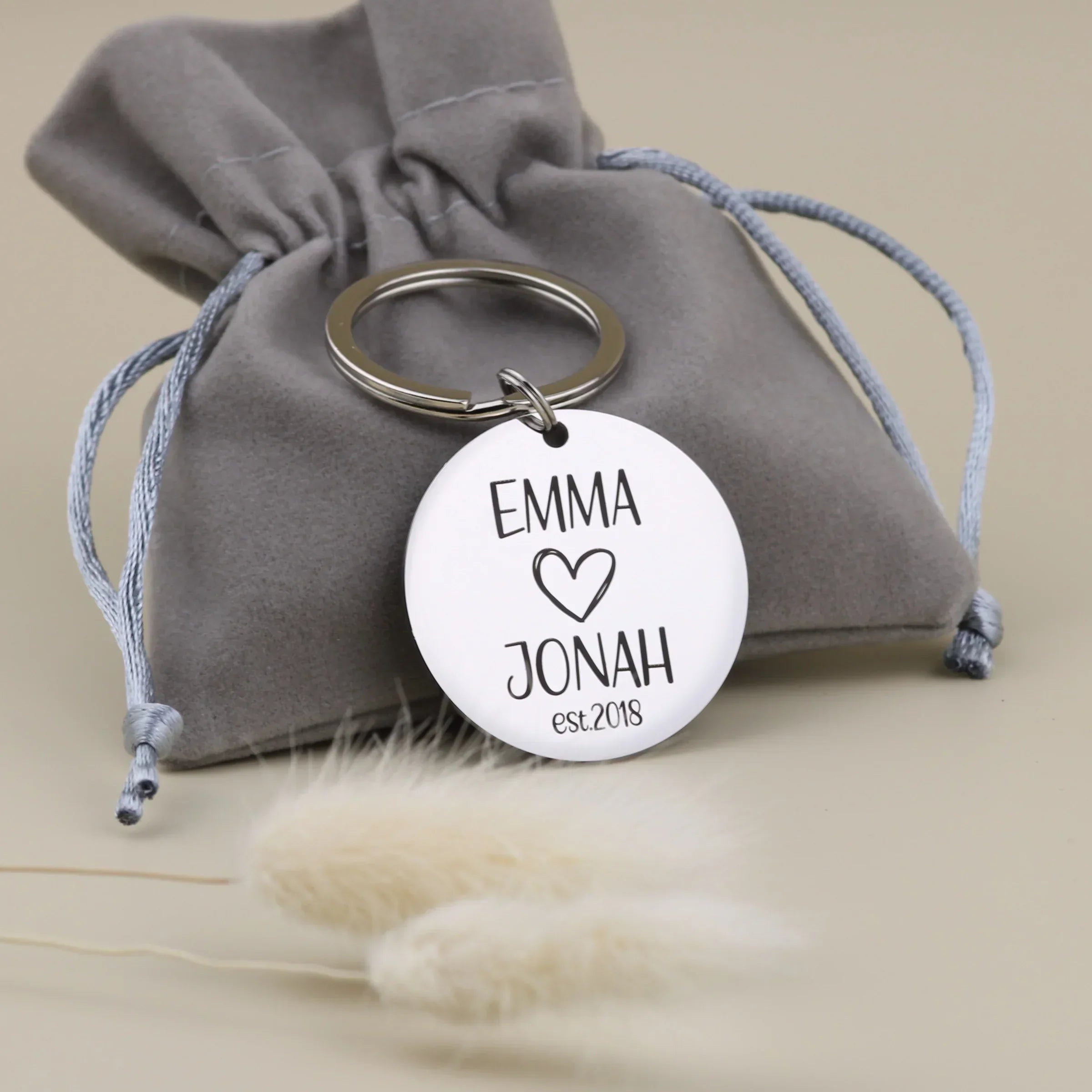 Personalisierter Paar-Schlüsselanhänger von Gravur19 mit grauem Samtsäckchen als Geschenkverpackung zum Jahrestag.