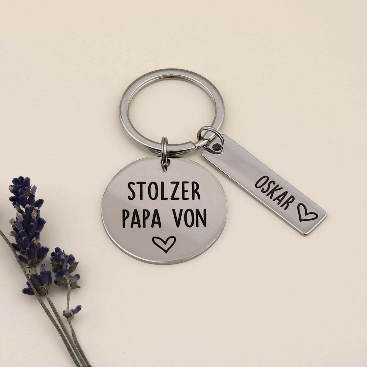 Schlüsselanhänger „Stolzer Papa von“ mit Namensanhänger Oskar und Lavendel dekoriert.

