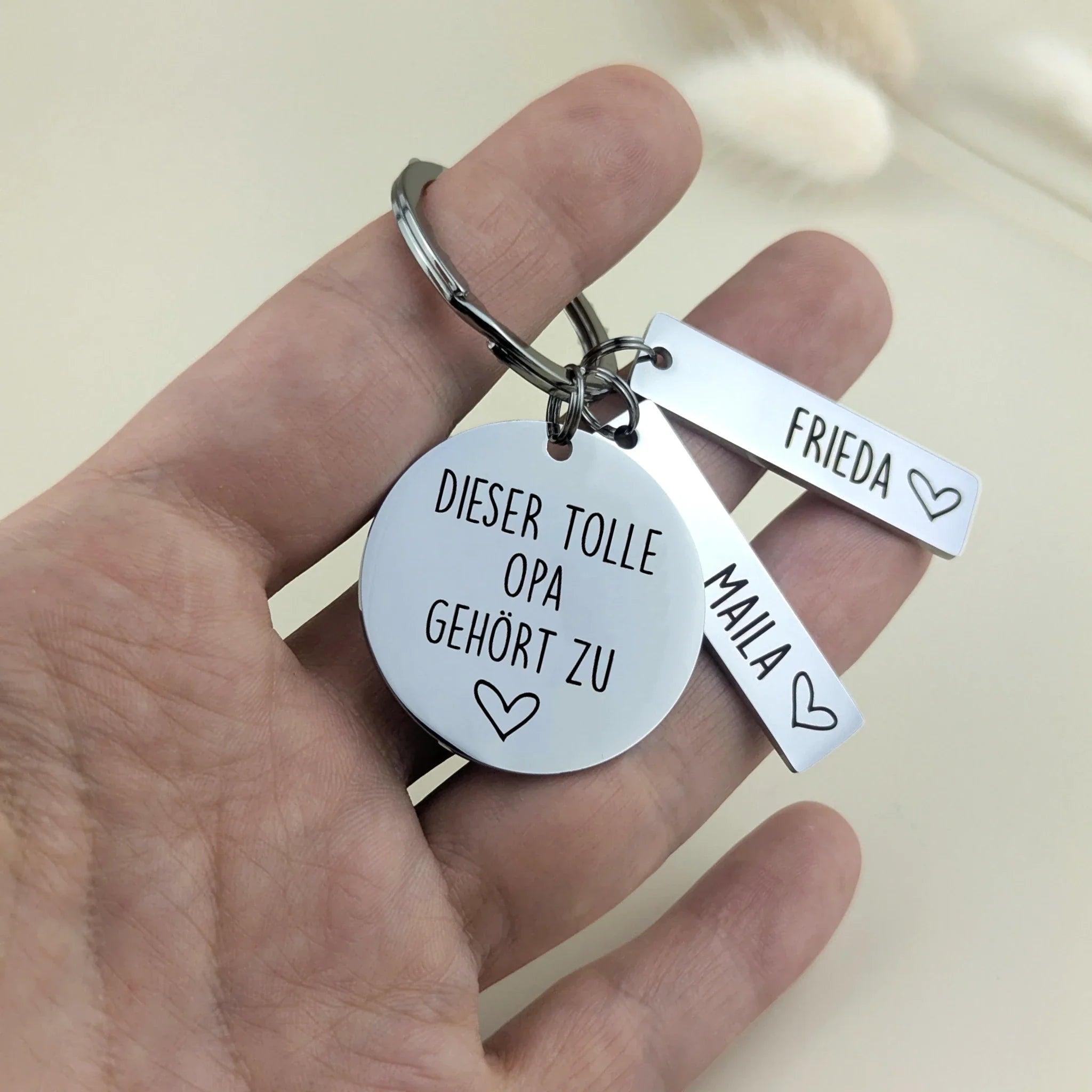 Tolle Opa Schlüsselanhänger mit Namensanhängern in der Hand als Größenvergleich